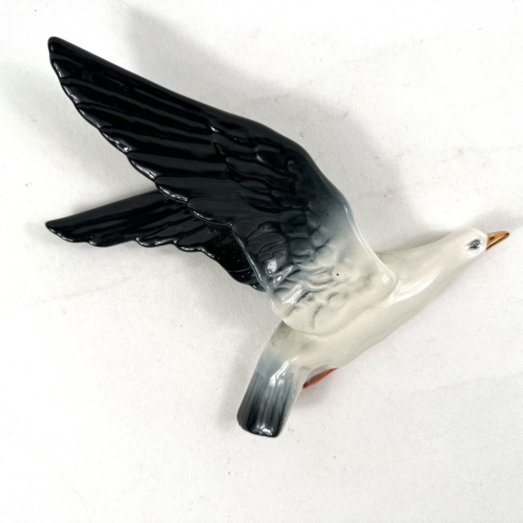 Vintage ceramic seabird figurine with black and white glazing, captured in graceful diving position with fine detailing