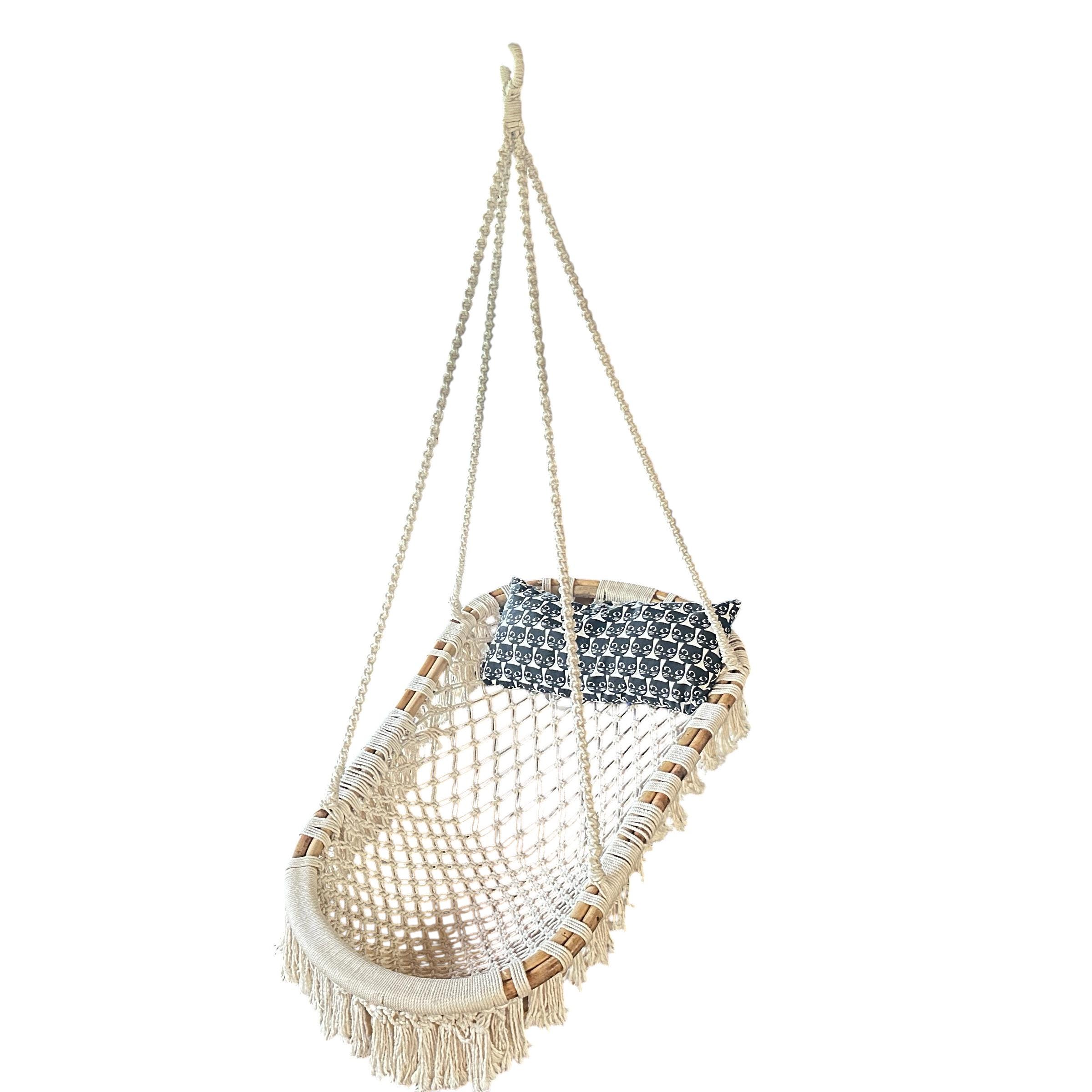 Centered front view of bohemian hanging chair with cream macramé seat and metal hanging hardware against neutral background