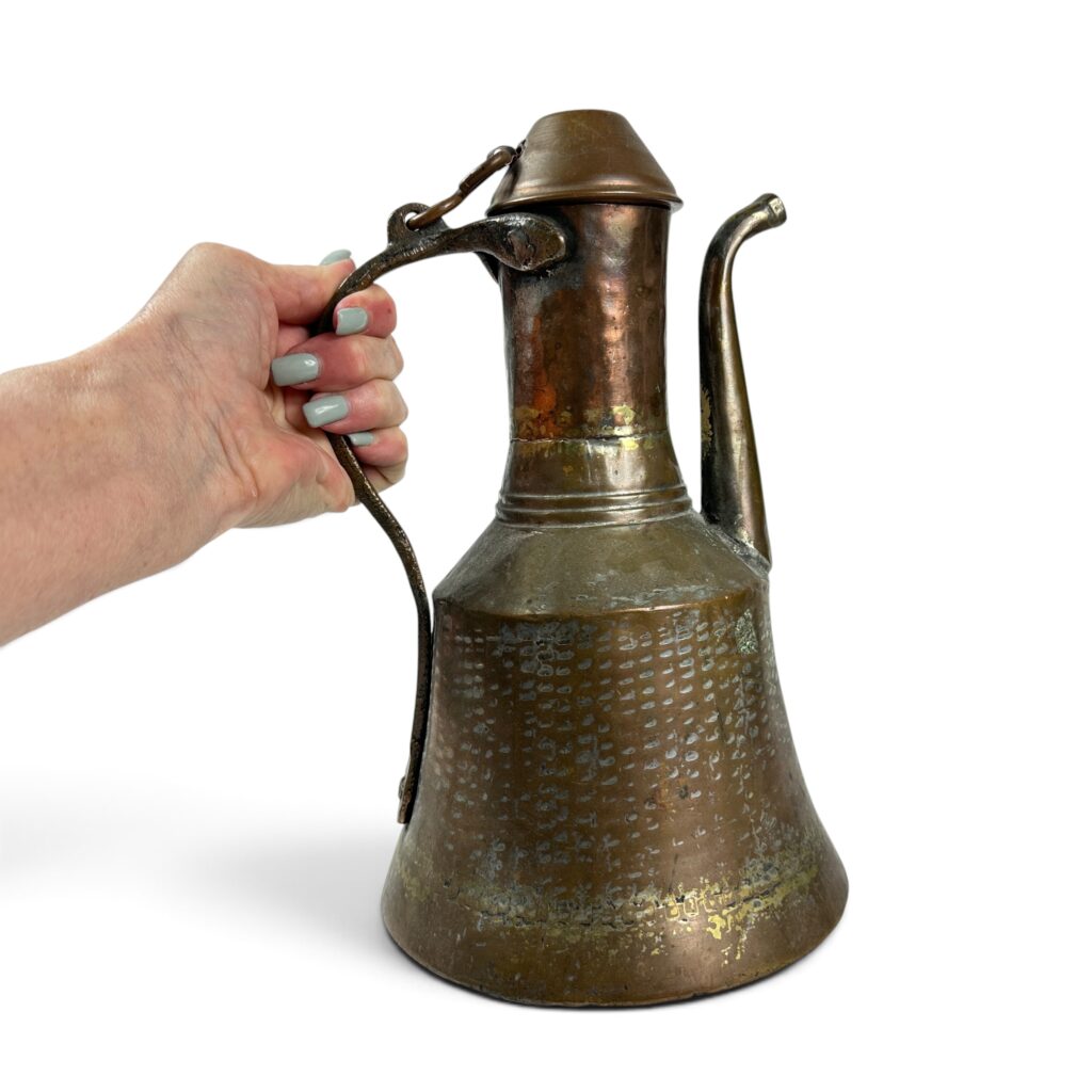 Vintage copper or bronze hinged pitcher with decorative hammered surface texture and curved spout
