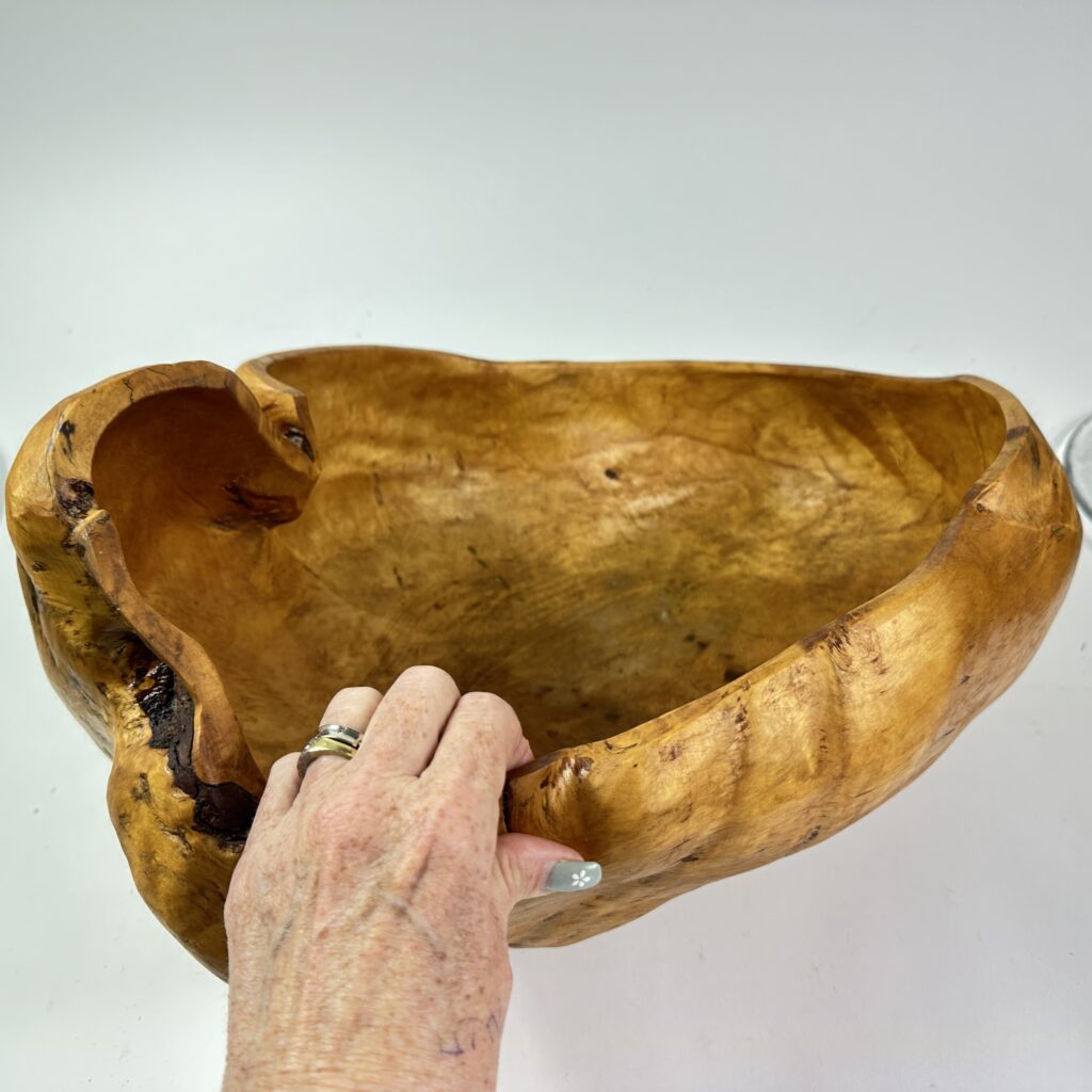 Large burl wood bowl with organic curved shape, displaying rich grain patterns and natural finish held in hands